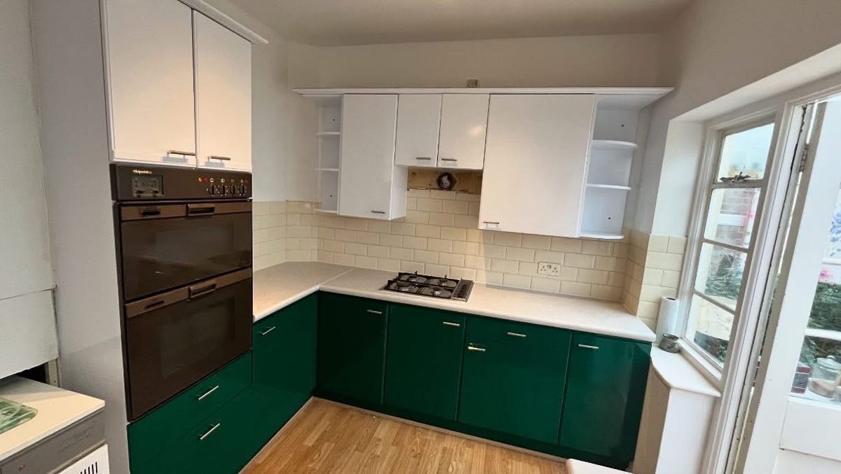 Kitchen after wrapping: gloss green base units, gloss white wall units and light worktops