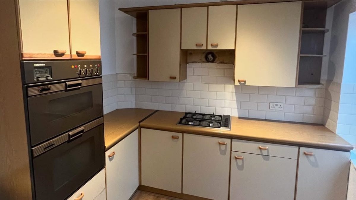 Kitchen before wrapping: dated cream doors with wood trim and brown worktops