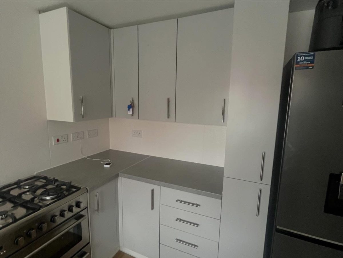 Kitchen after wrapping: light grey doors and drawers with grey worktops and bar handles